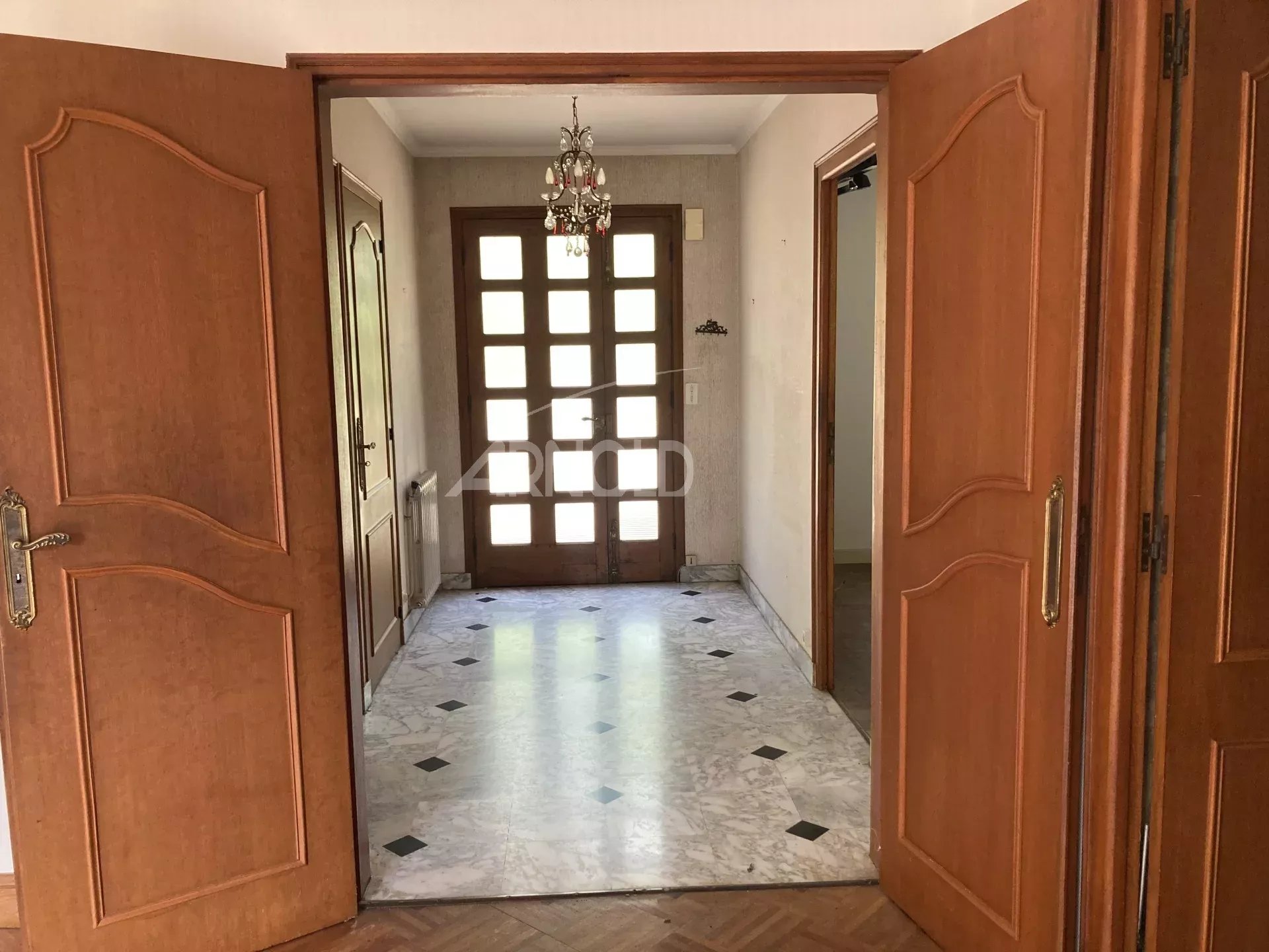 Entrée d'une maison spacieuse avec double porte en bois et carrelage au sol.