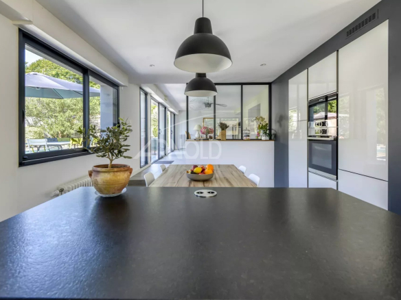 Interior of a modern kitchen with a black worktop and a view of the garden.