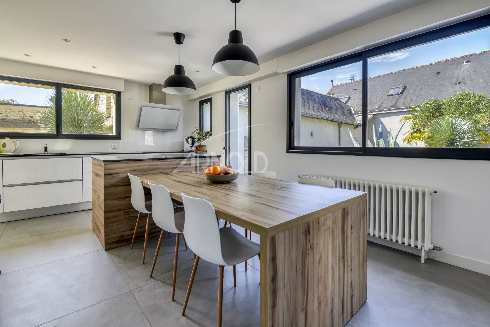 Contemporary cuisine in Nantes Modern kitchen with wooden table and white chairs, windows overlooking the outside.