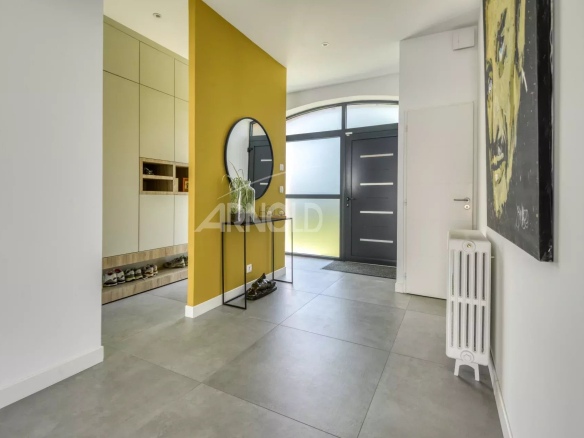 Entrance to a modern home with a yellow wall and a mirror, grey tiled floor.