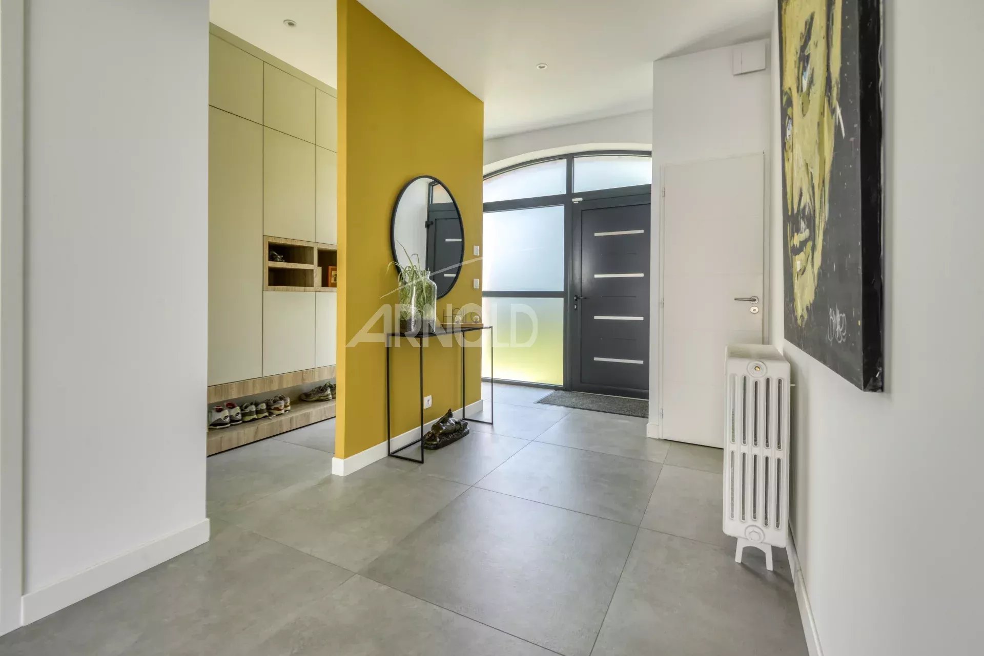 Entrance to a house in Nantes Entrance to a modern home with a yellow wall and a mirror, grey tiled floor.