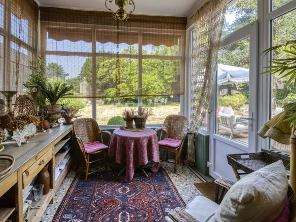 Véranda d'une maison bourgeoise à Saint-Étienne-de-Montluc avec mobilier chaleureux et vue sur le jardin.
