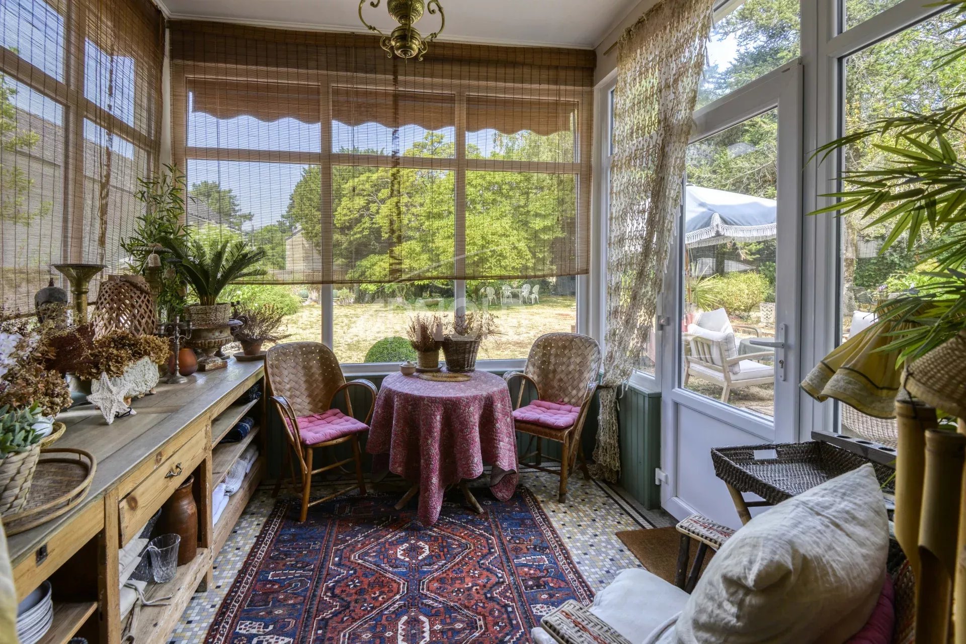 Véranda d’une maison bourgeoise Véranda d'une maison bourgeoise à Saint-Étienne-de-Montluc avec mobilier chaleureux et vue sur le jardin.