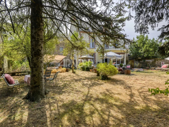 Jardin d'une maison bourgeoise à Saint-Étienne-de-Montluc, avec des chaises et des parasols.