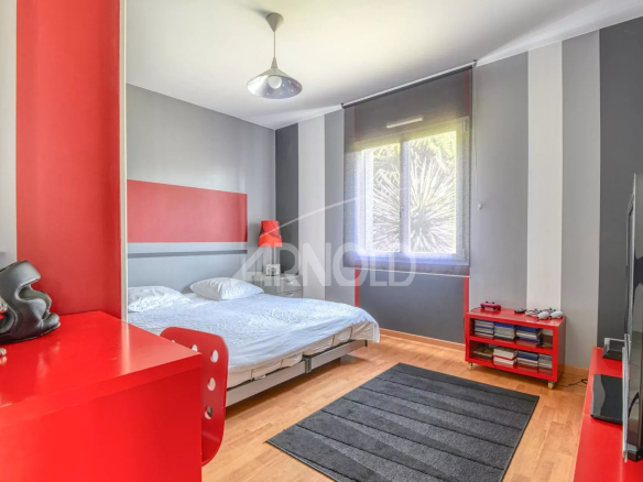 Chambre d'une maison contemporaine avec lit, meuble rouge et tapis noir.
