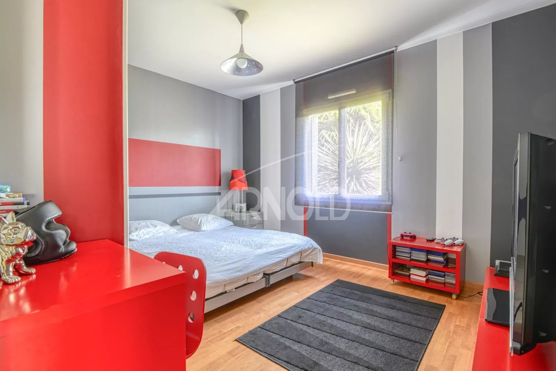 Chambre d'une maison contemporaine avec lit, meuble rouge et tapis noir.