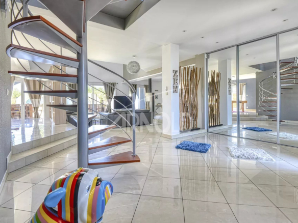 Intérieur d'une maison contemporaine avec un escalier en colimaçon et un salon lumineux.