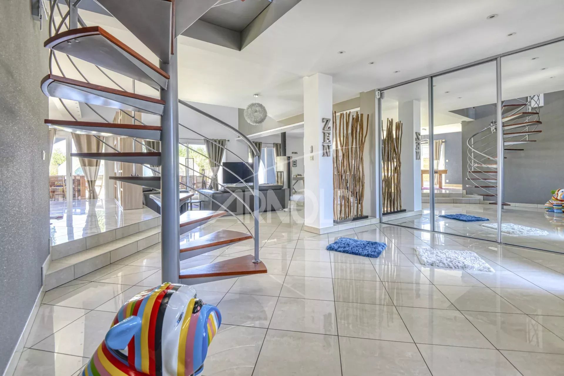 Intérieur d'une maison contemporaine avec un escalier en colimaçon et un salon lumineux.