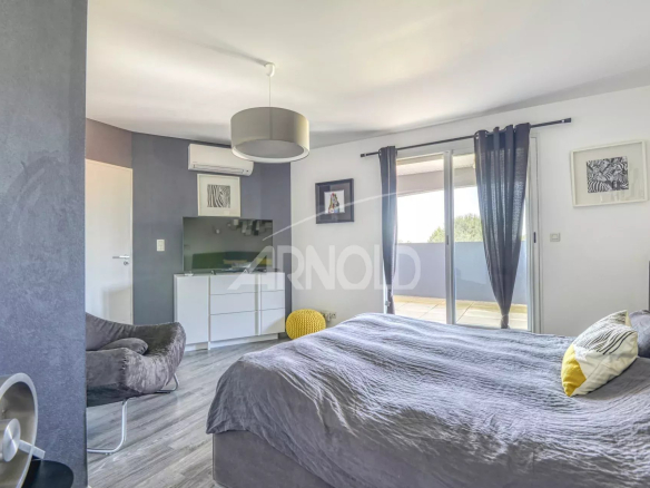 Chambre moderne avec lit double et accès à un balcon, décorée avec des couleurs neutres.