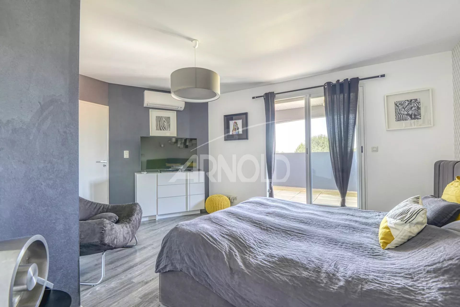 Chambre moderne avec lit double et accès à un balcon, décorée avec des couleurs neutres.
