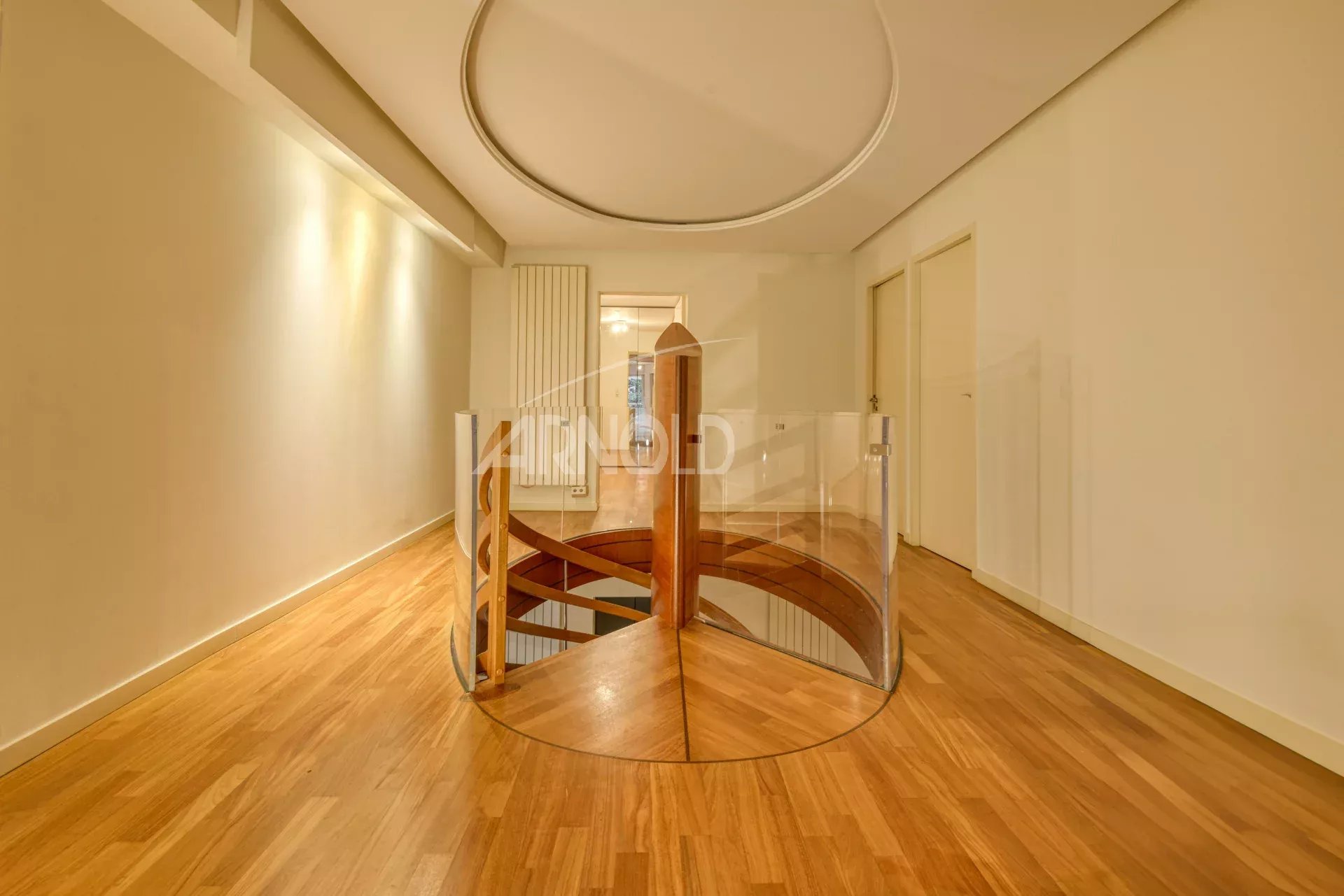 Interior staircase of a 7-room apartment in Nantes Wooden staircase with glass railing in a modern apartment.