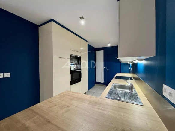 Modern kitchen in a 7-room apartment in Nantes, with wooden worktops and blue walls.