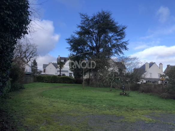 Terrain constructible de 2022 m² à Vannes, avec arbres et maisons environnantes.