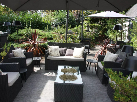 Terrasse aménagée avec mobilier de jardin dans une maison à Belz, entourée de verdure.