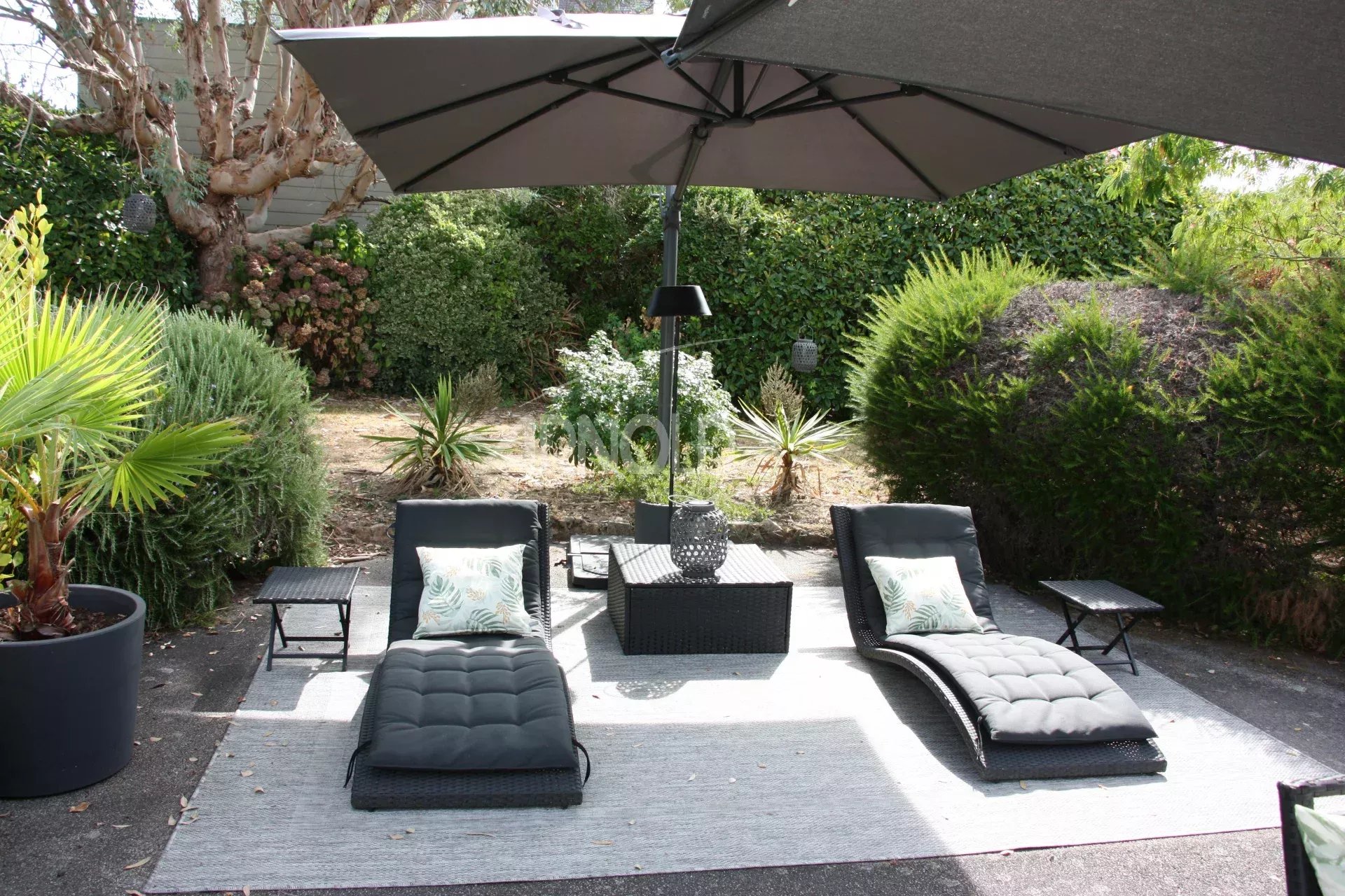 Espace extérieur de la maison à Belz Espace extérieur avec chaises longues et parasol dans un jardin verdoyant.