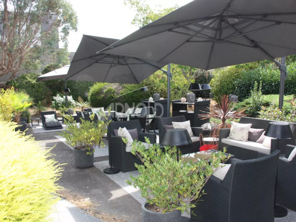 Terrasse aménagée avec parasols et mobilier de jardin dans un espace verdoyant à Belz.