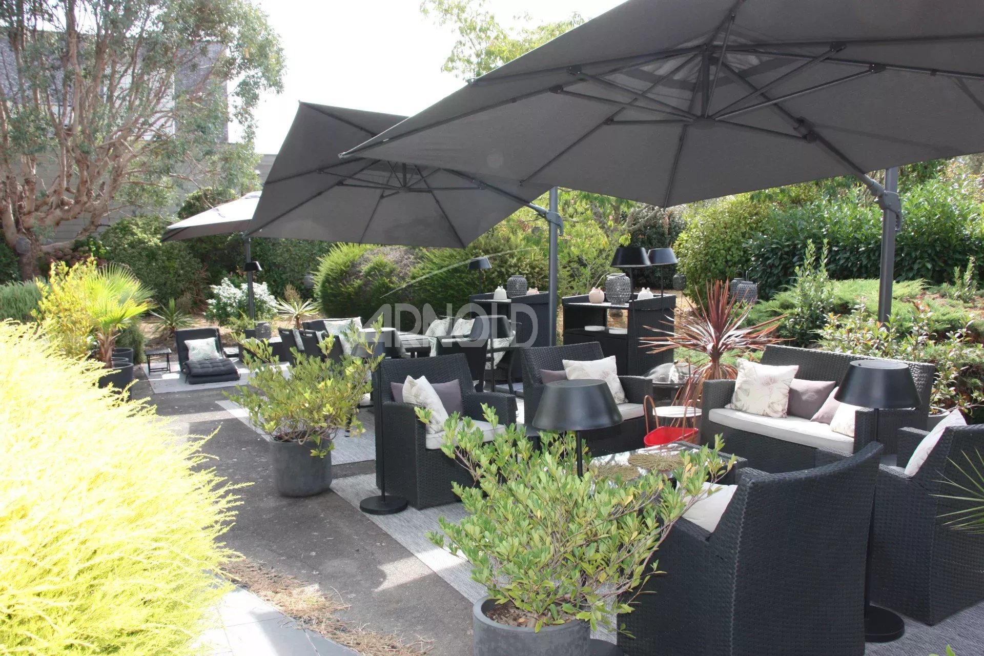 Terrasse de maison à Belz Terrasse aménagée avec parasols et mobilier de jardin dans un espace verdoyant à Belz.