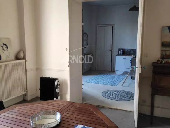 Interior of a bourgeois house to be renovated in Vannes, view of a room with a wooden table and an open door.