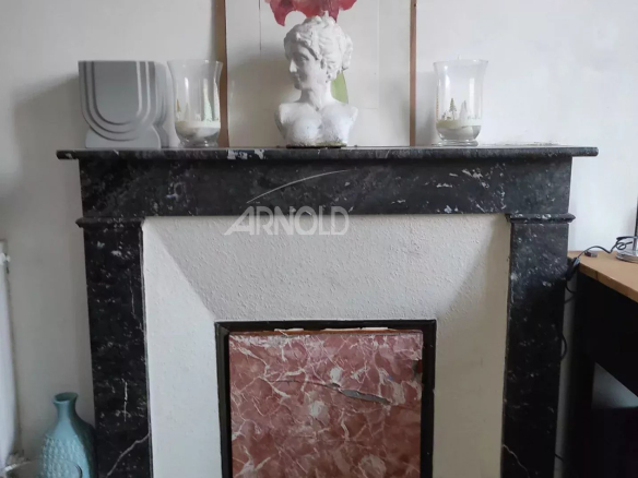 Marble fireplace with a statue and decorations on an interior wall.