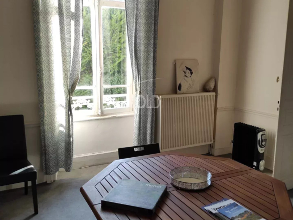 Interior of a bourgeois house to be renovated in Vannes, with a wooden table and curtains.