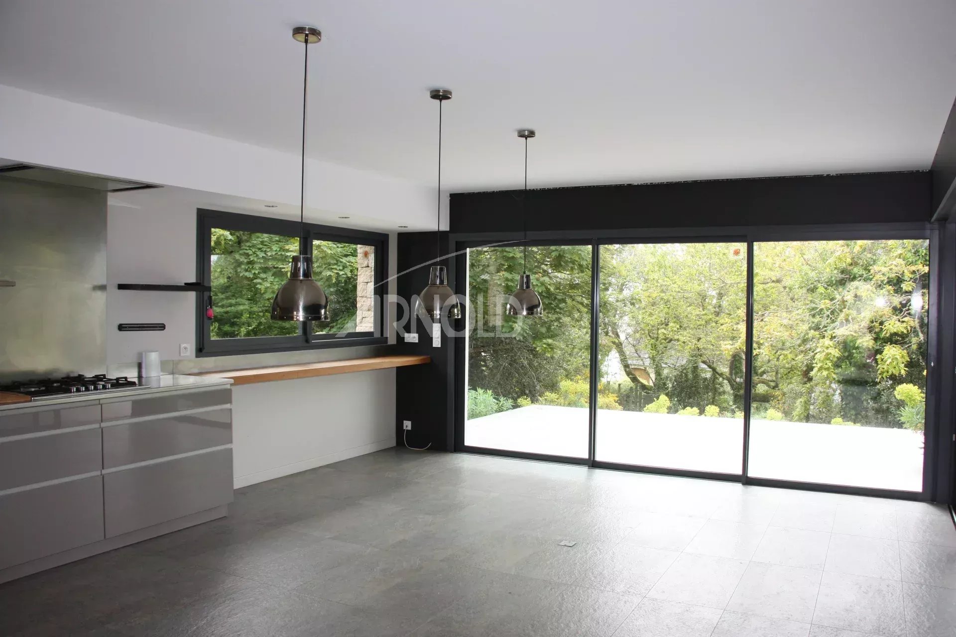 Intérieur lumineux d’une maison familiale à Sarzeau Intérieur d'une maison familiale avec cuisine moderne et grandes fenêtres donnant sur un jardin verdoyant.