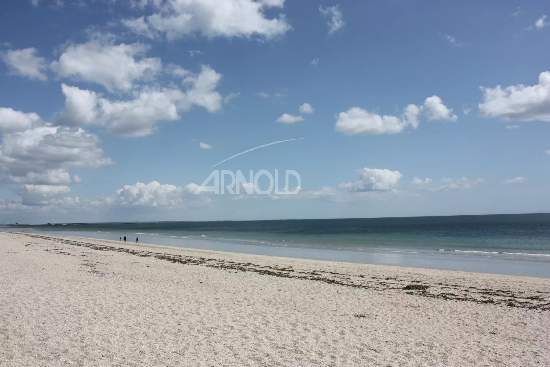 Plage à Sarzeau Plage de sable fin avec des personnes au bord de l'eau, ciel bleu et nuages