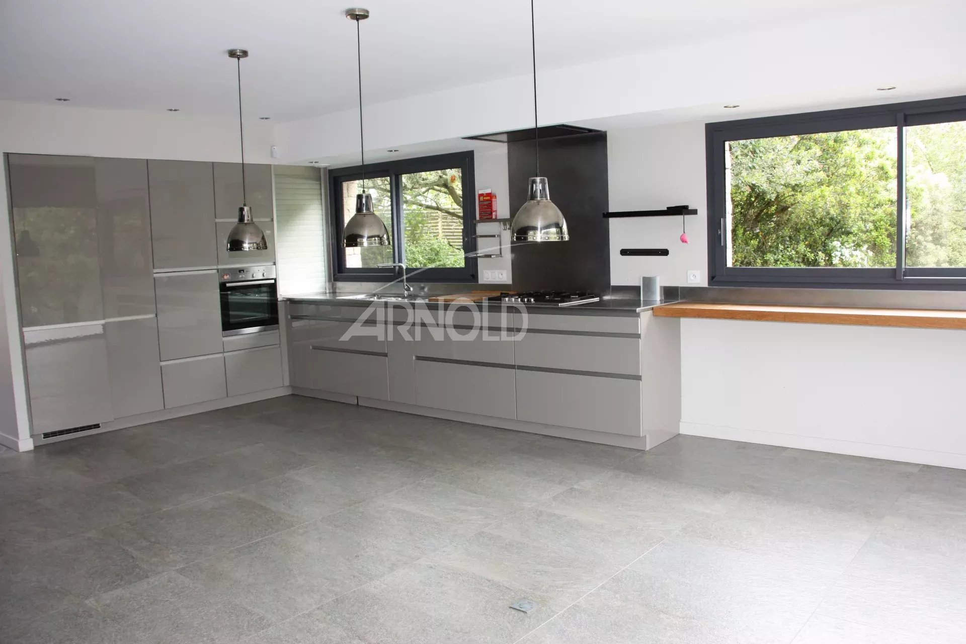 Cuisine rénovée de maison familiale Cuisine moderne et lumineuse avec îlot central, fenêtres donnant sur l'extérieur.