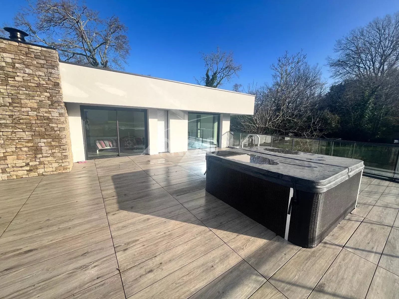 Terrasse avec jacuzzi d’une maison contemporaine Terrasse d'une maison contemporaine avec jacuzzi à Vannes, entourée d'arbres.