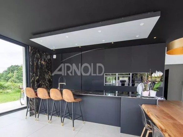 Cuisine moderne avec bar et grandes fenêtres donnant sur un jardin verdoyant.