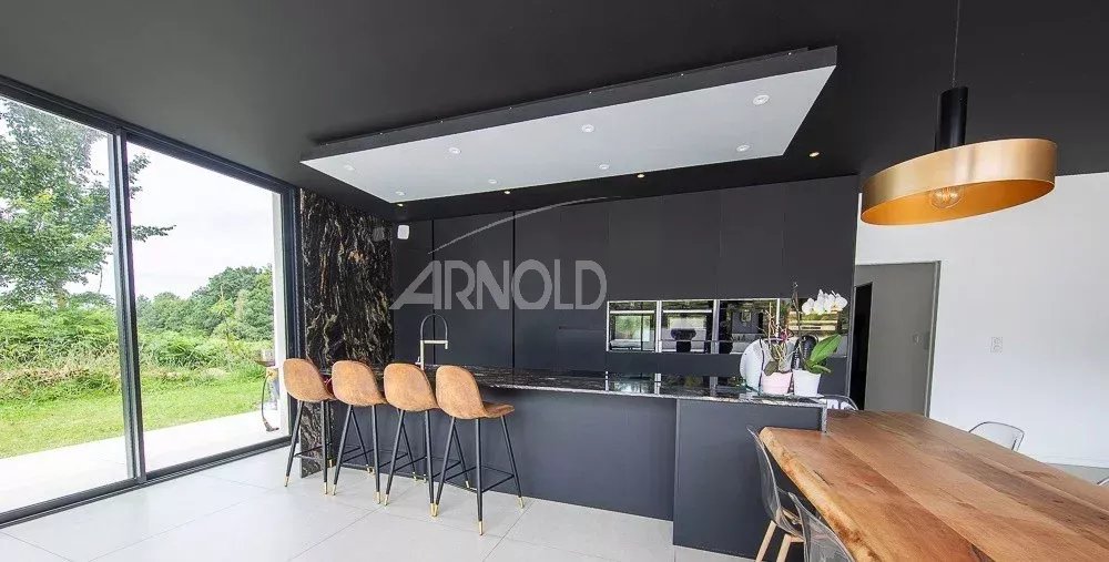 Cuisine contemporaine à Vannes Cuisine moderne avec bar et grandes fenêtres donnant sur un jardin verdoyant.