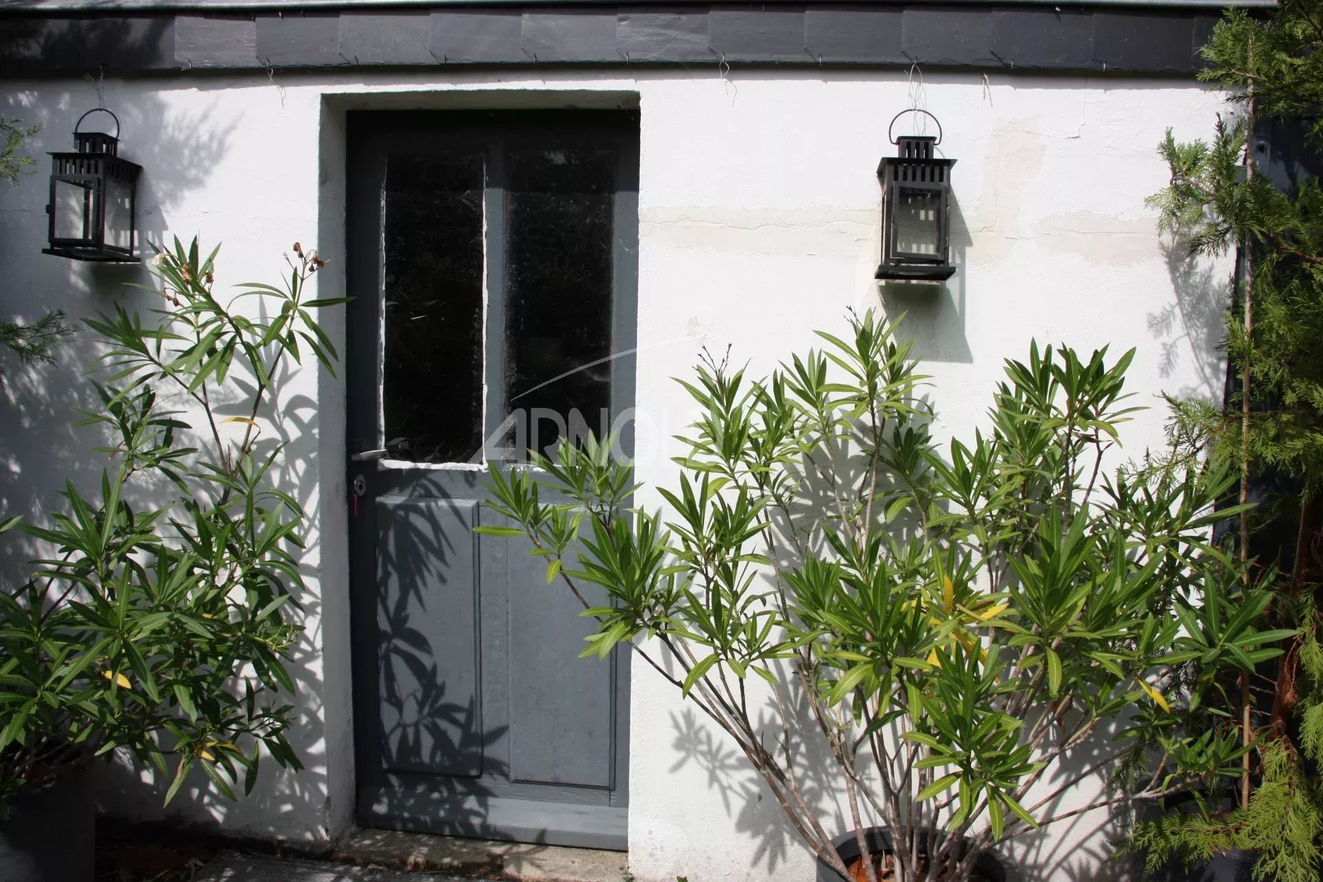 Entrance to a charming house in Belz, with lanterns and plants in front of the door.