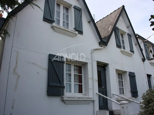 Charming house in Belz with white facade and blue shutters, surrounded by greenery.