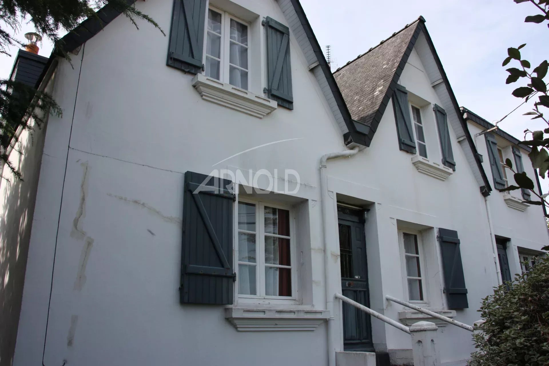 Charming house in Belz with white facade and blue shutters, surrounded by greenery.