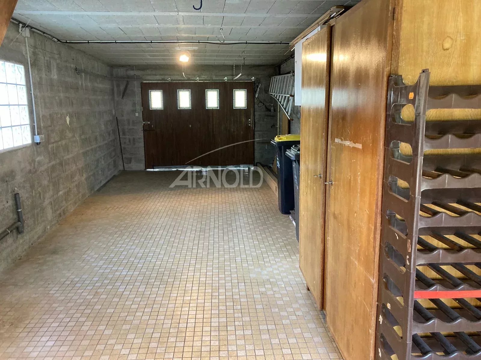 Intérieur d'un garage spacieux avec des murs en béton et des portes en bois.