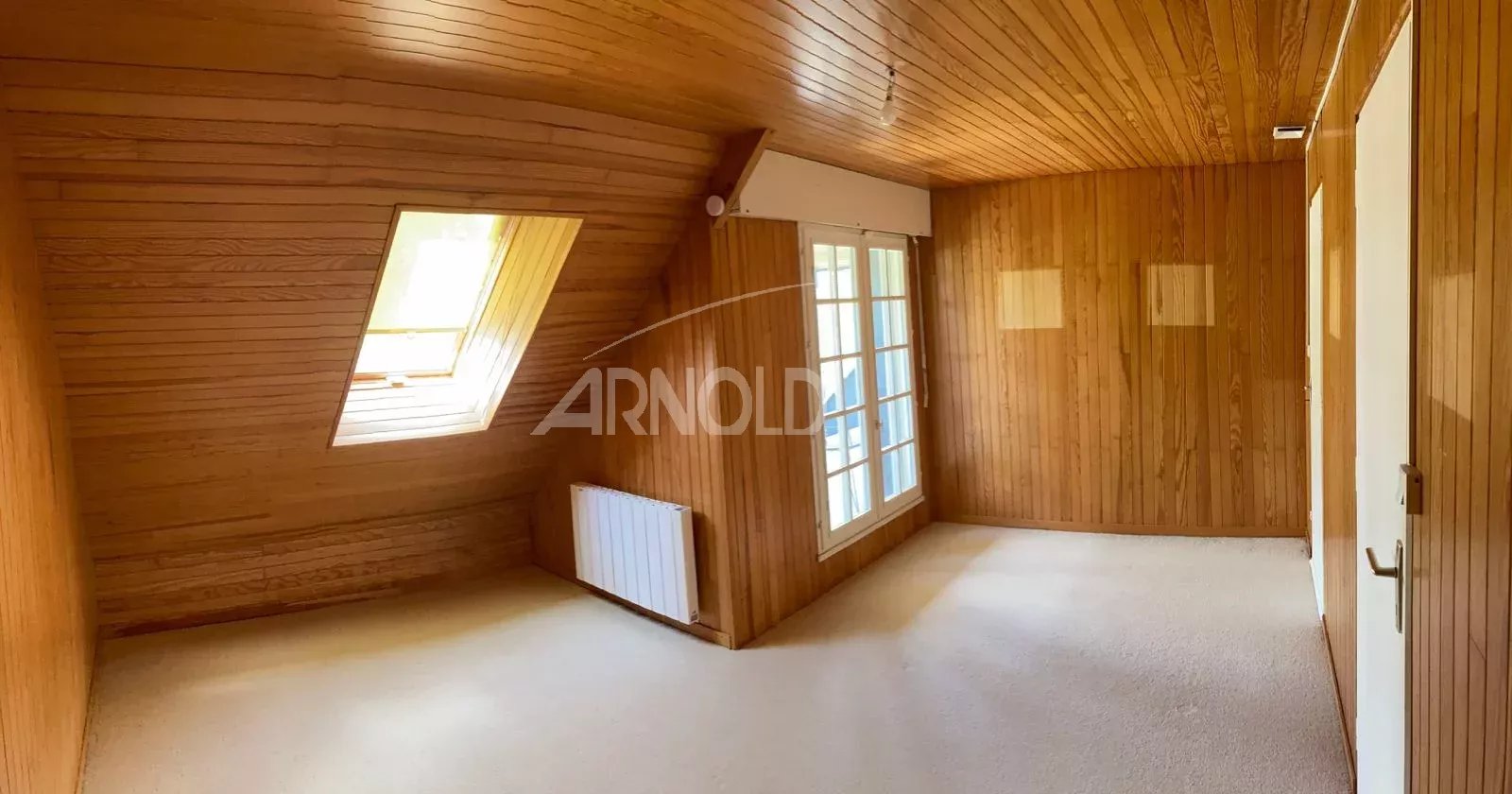 Intérieur d'une maison néo-bretonne à Vannes, avec des murs en bois et une fenêtre donnant sur l'extérieur.