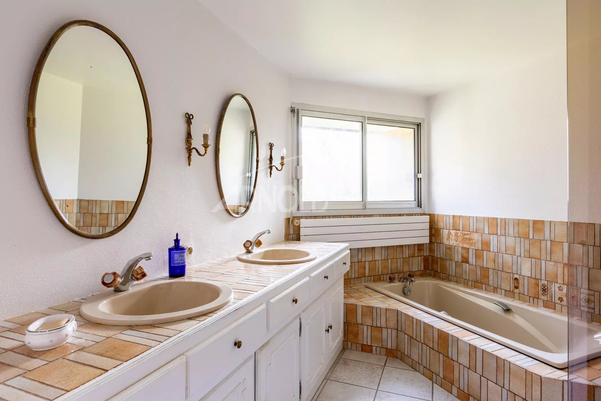 Salle de bain contemporaine Salle de bain moderne avec deux lavabos, baignoire et fenêtres, décorée de carrelage beige.