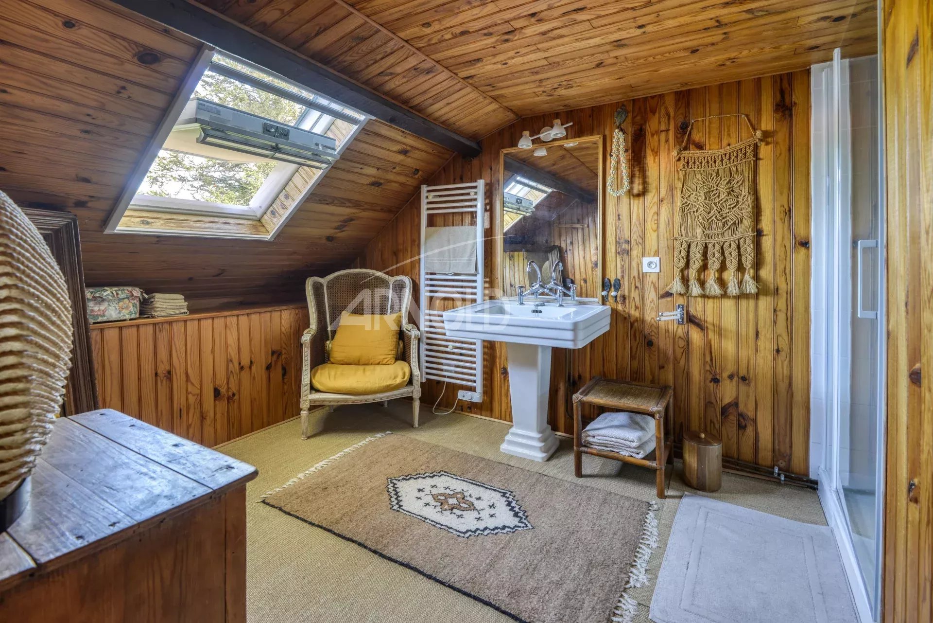 Salle de bain chaleureuse Salle de bain avec poutres en bois, lavabo et fenêtre de toit dans une maison à Saint-Étienne-de-Montluc.