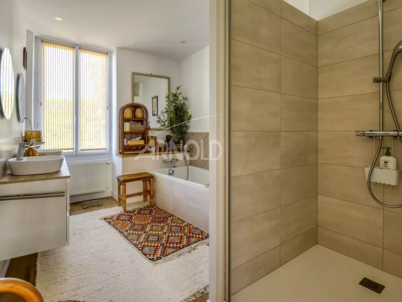 Salle de bain moderne avec baignoire, douche et décoration chaleureuse à Saint-Étienne-de-Montluc.
