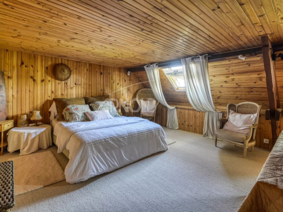 Chambre chaleureuse avec poutres en bois et décoration simple, située dans une maison à Saint-Étienne-de-Montluc.