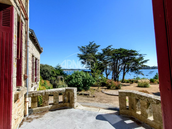 Terrasse d'une propriété avec vue sur le Golfe du Morbihan, entourée de verdure.