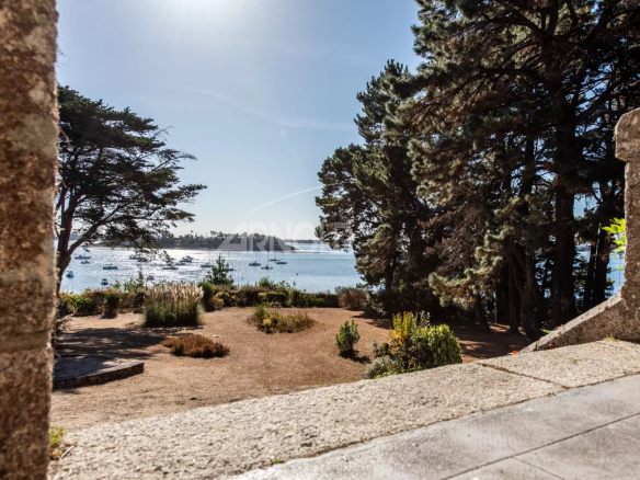 Vue panoramique sur le Golfe du Morbihan depuis une terrasse entourée d'arbres.