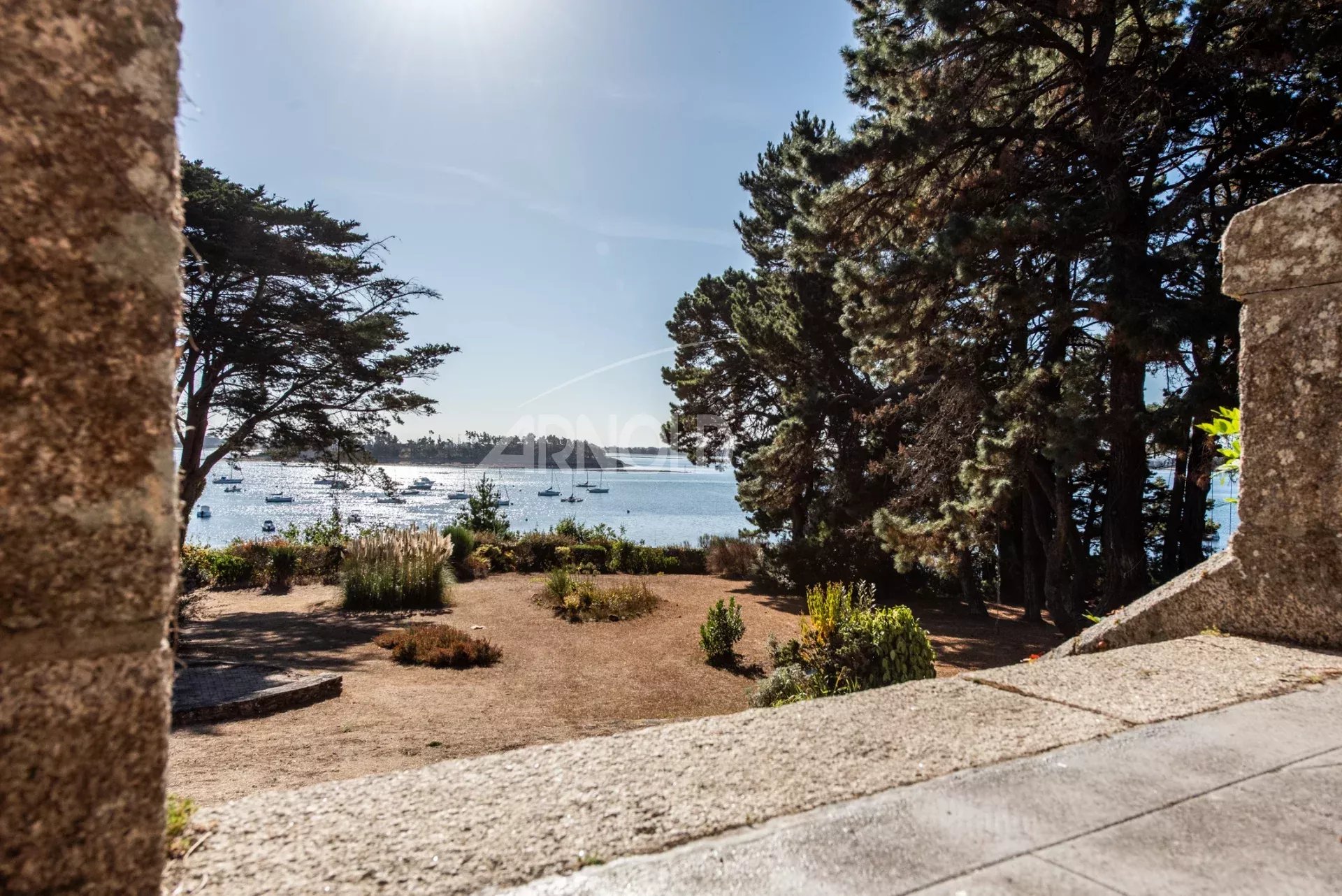 Terrasse avec vue sur le Golfe du Morbihan Vue panoramique sur le Golfe du Morbihan depuis une terrasse entourée d'arbres.