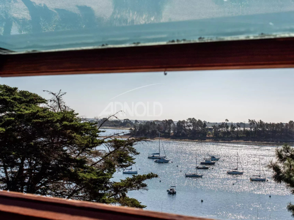 Vue panoramique sur le Golfe du Morbihan depuis une terrasse avec des bateaux au loin.