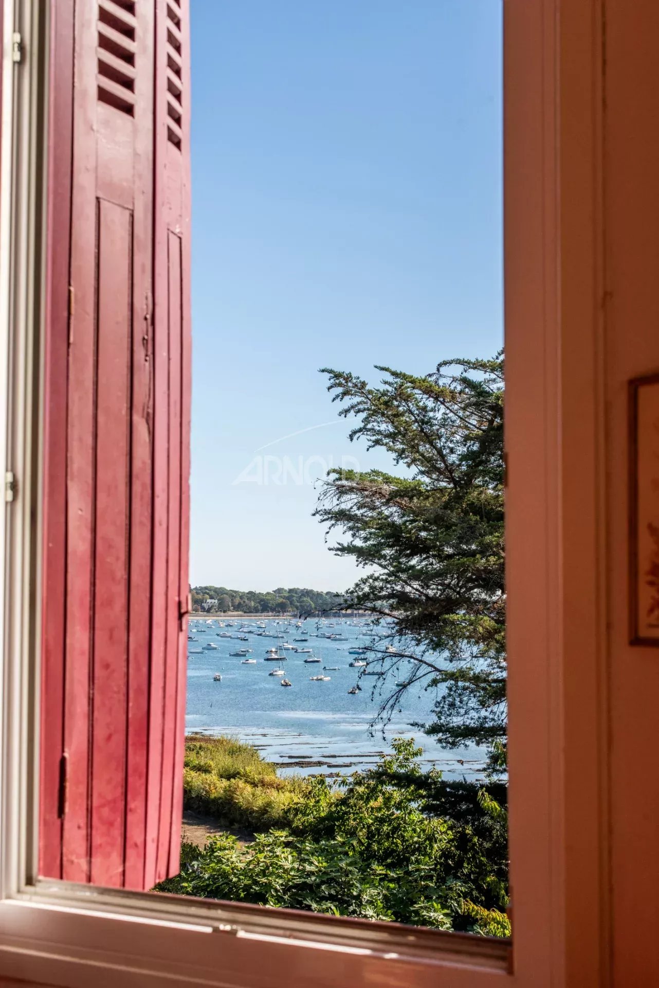 Vue sur le Golfe du Morbihan Vue panoramique sur le Golfe du Morbihan depuis une fenêtre avec volets rouges.