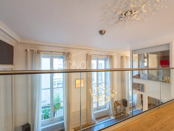 Intérieur d'un duplex de 127 m² avec balustrade en verre et lumière naturelle à Paris 9ème.
