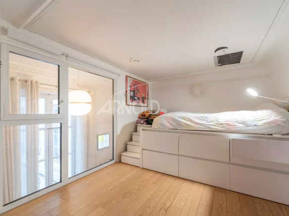 Chambre en duplex avec lit surélevé et fenêtres lumineuses dans un appartement à Paris 9ème.