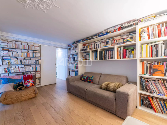 Intérieur d'un duplex à Paris 9, avec un salon lumineux et des étagères remplies de livres.
