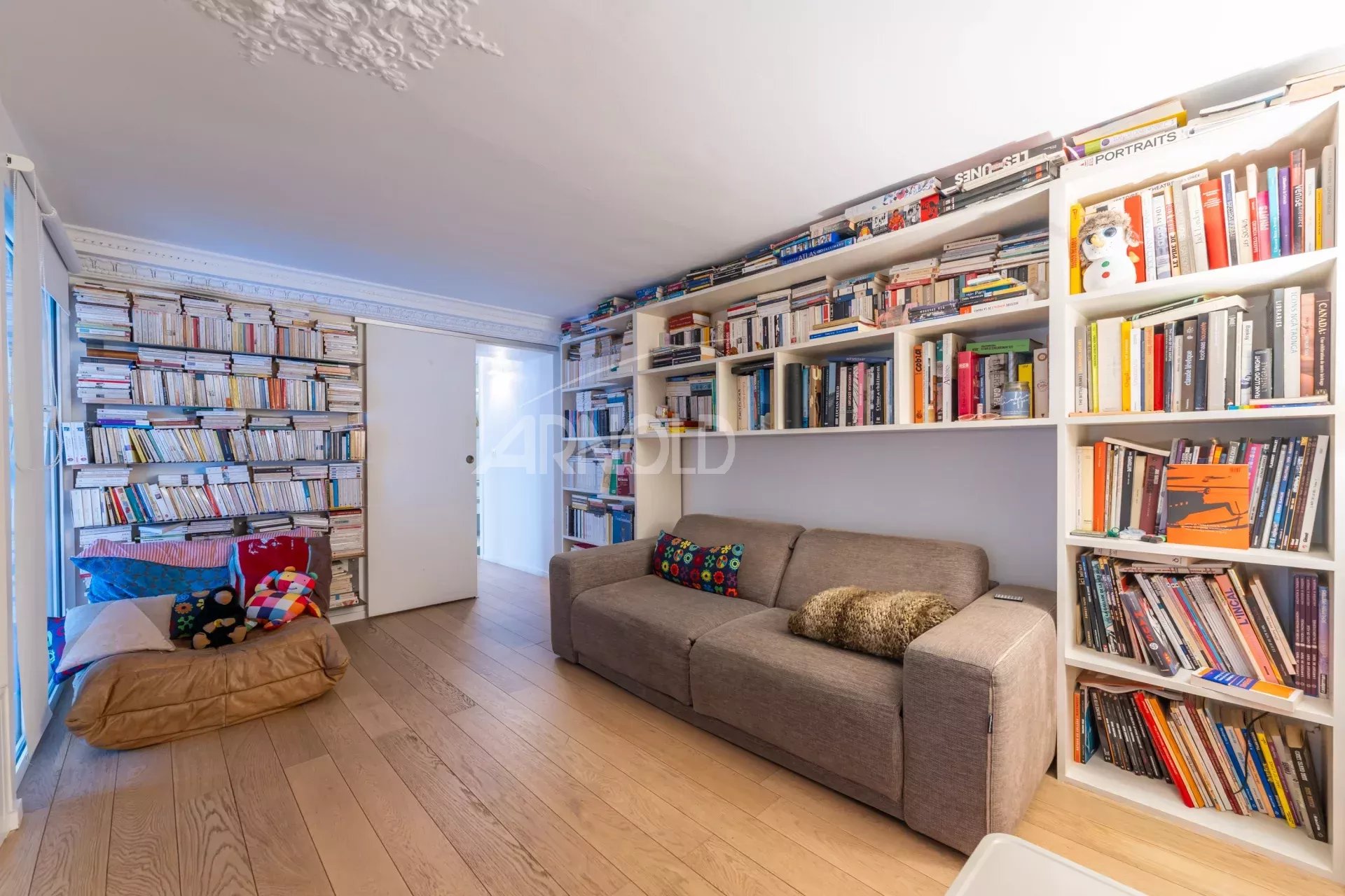 Duplex lumineux à Paris 9 Intérieur d'un duplex à Paris 9, avec un salon lumineux et des étagères remplies de livres.