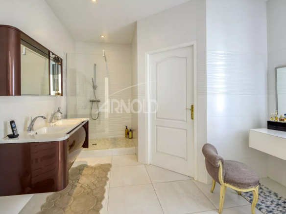 Salle de bain moderne avec baignoire et douche, meuble double vasque, carrelage clair.