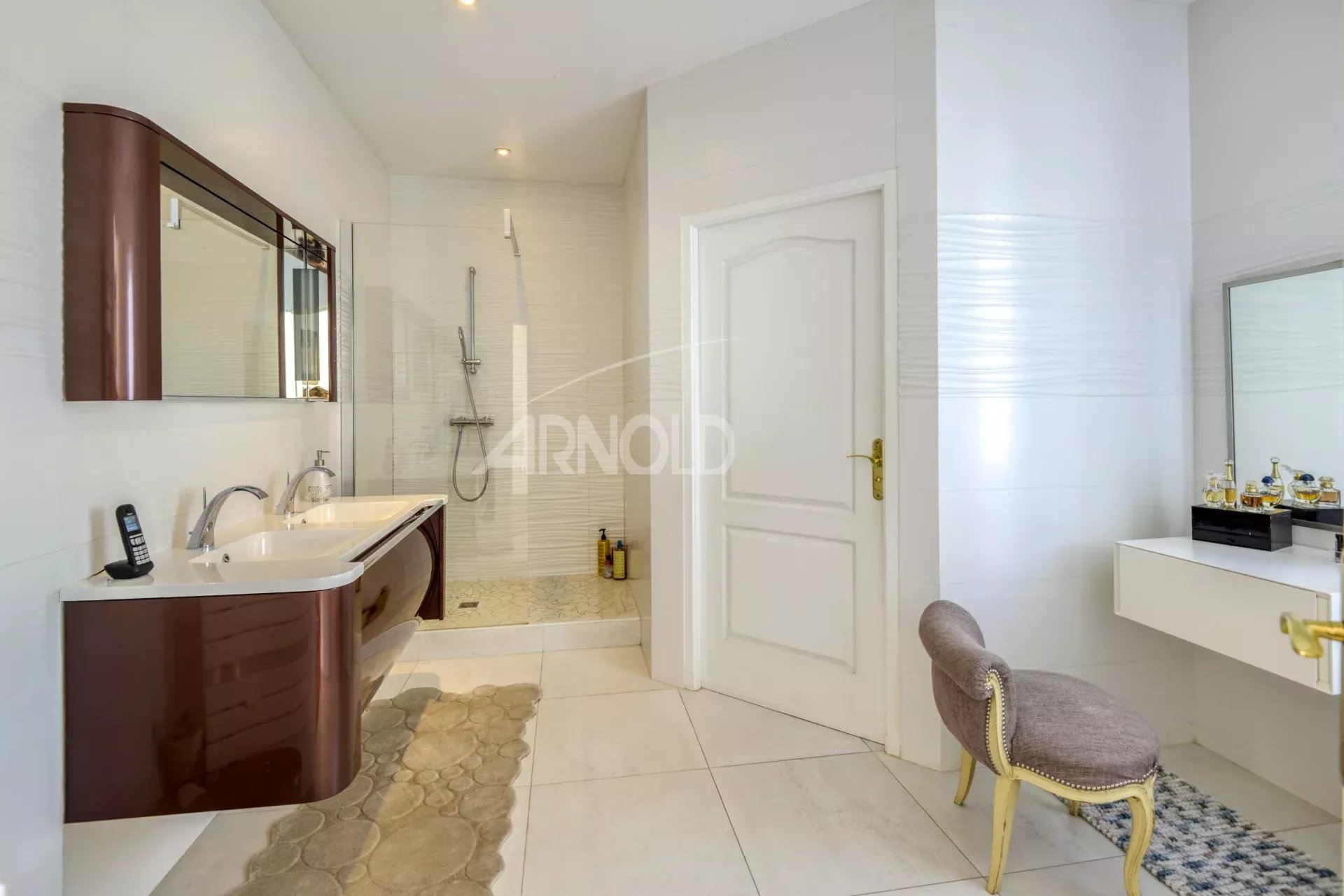 Salle de bain moderne avec baignoire et douche, meuble double vasque, carrelage clair.